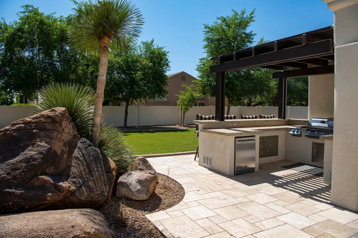 Outdoor kitchen and grill on a stone patio beside a palm