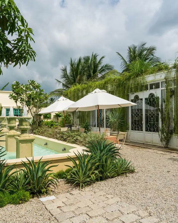 Gravel courtyard with a fountain, agave plants, palms and white umbrellas